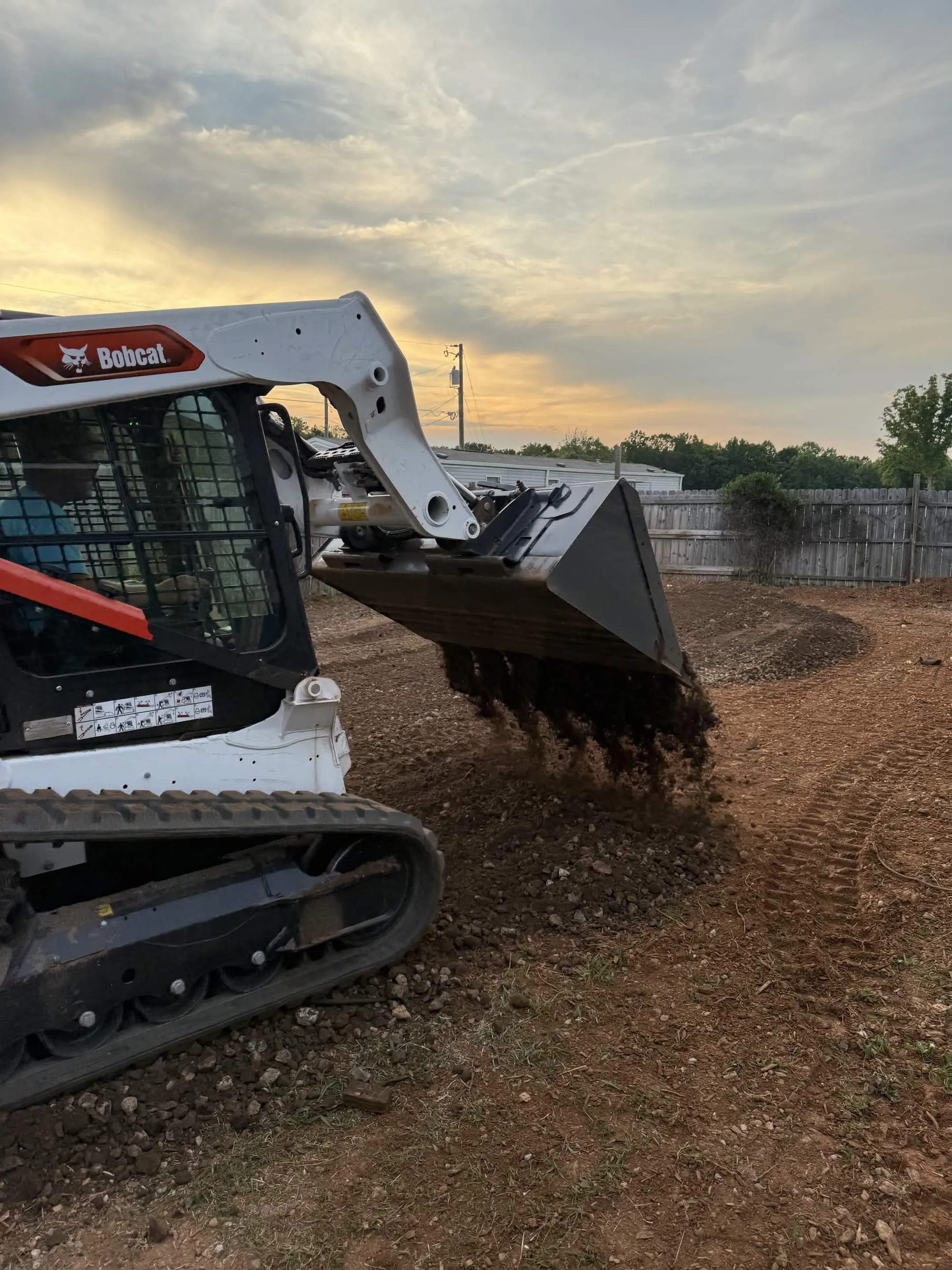 A track loader spreading soil across a graded site