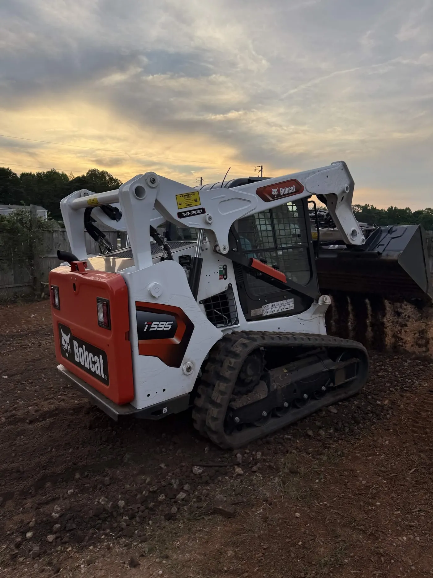 A T595 track loader grading a residential lot with a grading bucket